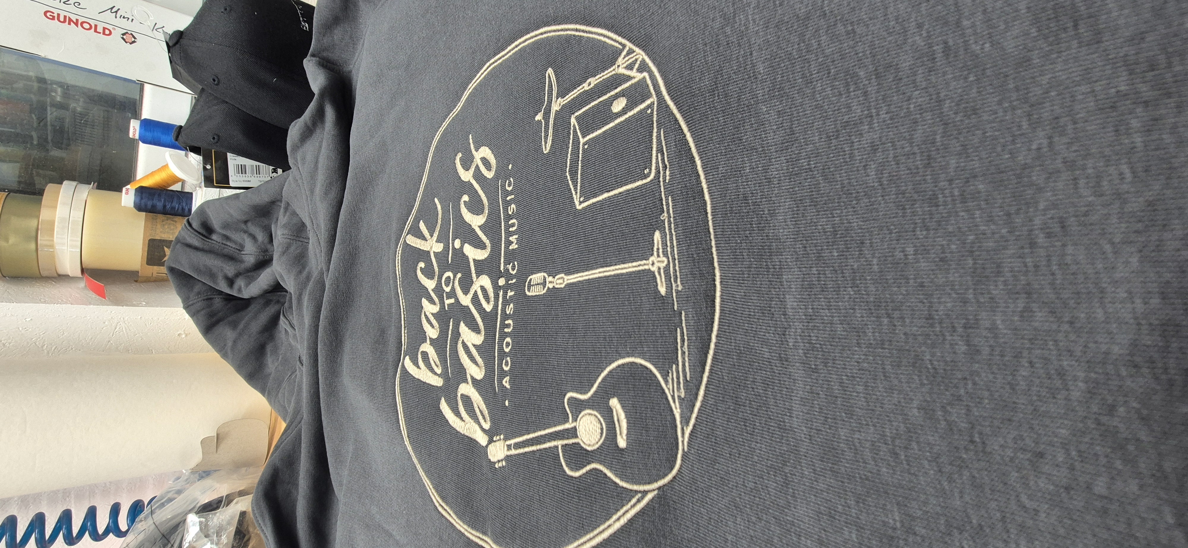 Detail der goldenen Back-to-basics-Stickerei auf einem dunklen Hoodie