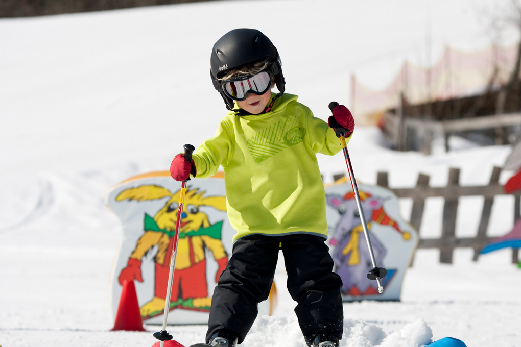 Kind mit Skilehrer im Schnee
