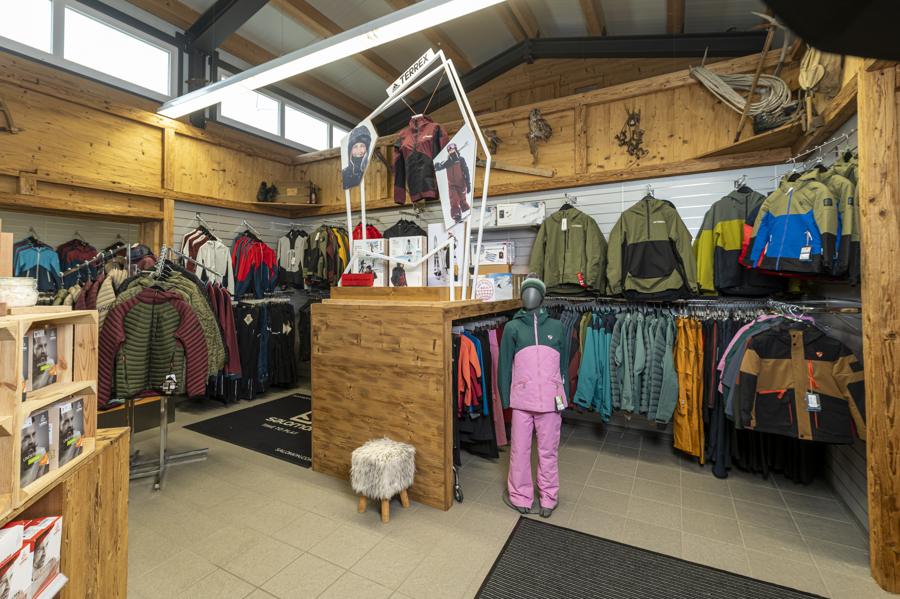 Innenansicht des Sportgeschäfts mit Sportbekleidung und Holztheke