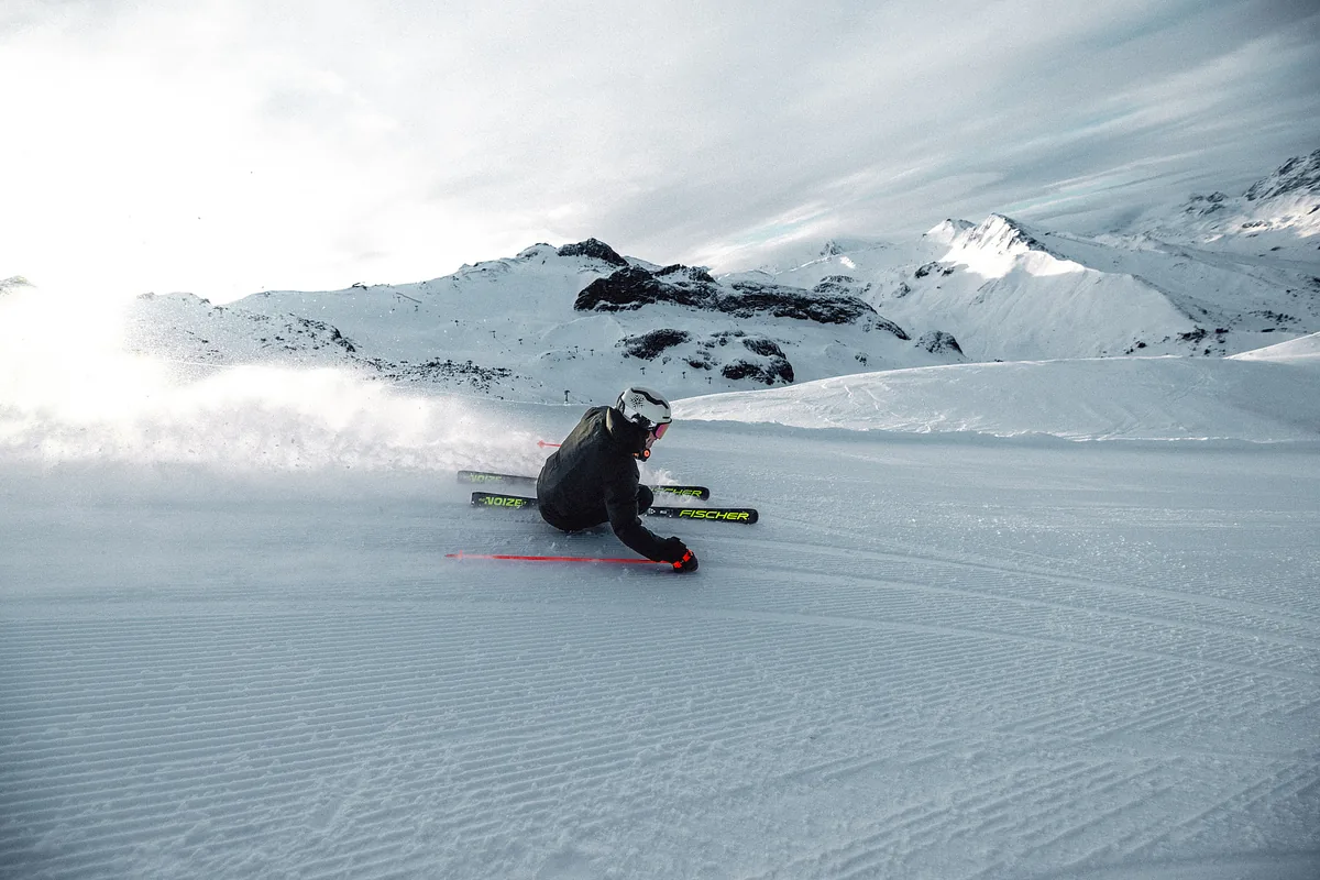 Skifahrer in sportlicher Kurvenlage auf einer alpinen Piste.